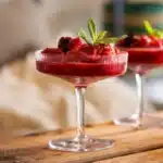 Raspberry-apple champagne slushies served in chilled coupe glasses, garnished with fresh raspberries and mint