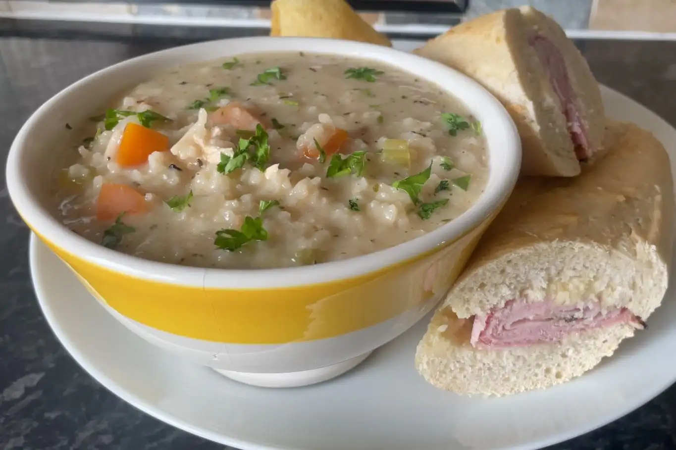 Bowl of Chopt spicy chicken soup recipe with rice, served with a side of sliced baguette.