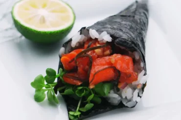 Freshly made Temaki Salmon Cream Cheese sushi with vibrant toppings and a lime garnish on the side.