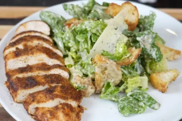 Plate of fresh Crispy Chicken Salad recipe with seasoned grilled chicken, romaine lettuce, croutons, and Parmesan cheese, served on a white dish