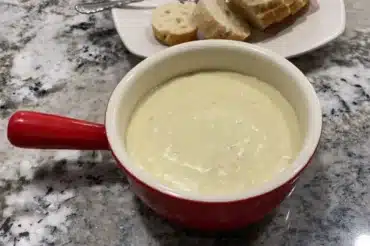 Delicious bowl of Chicken Velvet Soup served with soft bread slices on a granite countertop, perfect for a comforting meal.