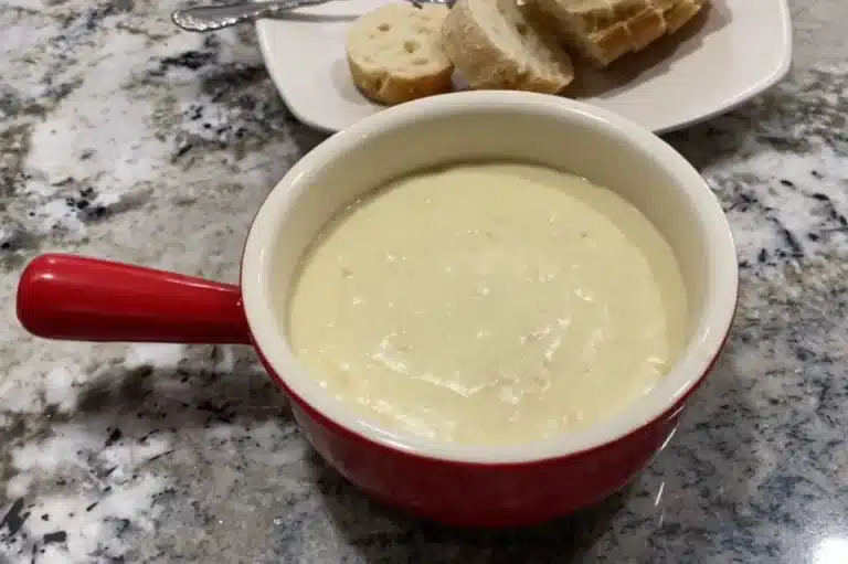 Delicious bowl of Chicken Velvet Soup served with soft bread slices on a granite countertop, perfect for a comforting meal.