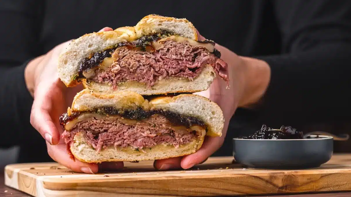 Knob Sandwich featuring layers of tender roast beef, melted cheese, and sweet chutney, sliced to showcase its delicious filling