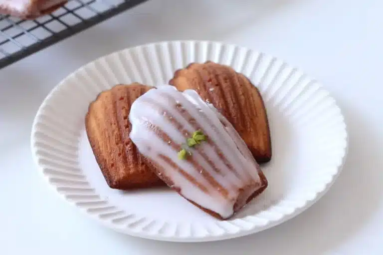 Freshly baked Madeleine cookies with a creamy texture, drizzled with sweet glaze and garnished with pistachios. Perfect for a Madeline Cookies Recipe Using Cream.