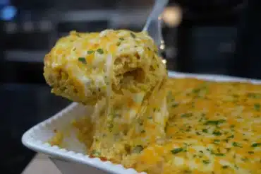 Mamaw's Chicken and Rice Casserole topped with melted cheddar cheese, served hot in a white baking dish.