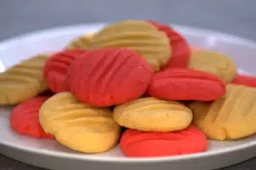 Plate of red and yellow cookies showcasing the use of colorful ingredients in some cookie recipes for a vibrant presentation.