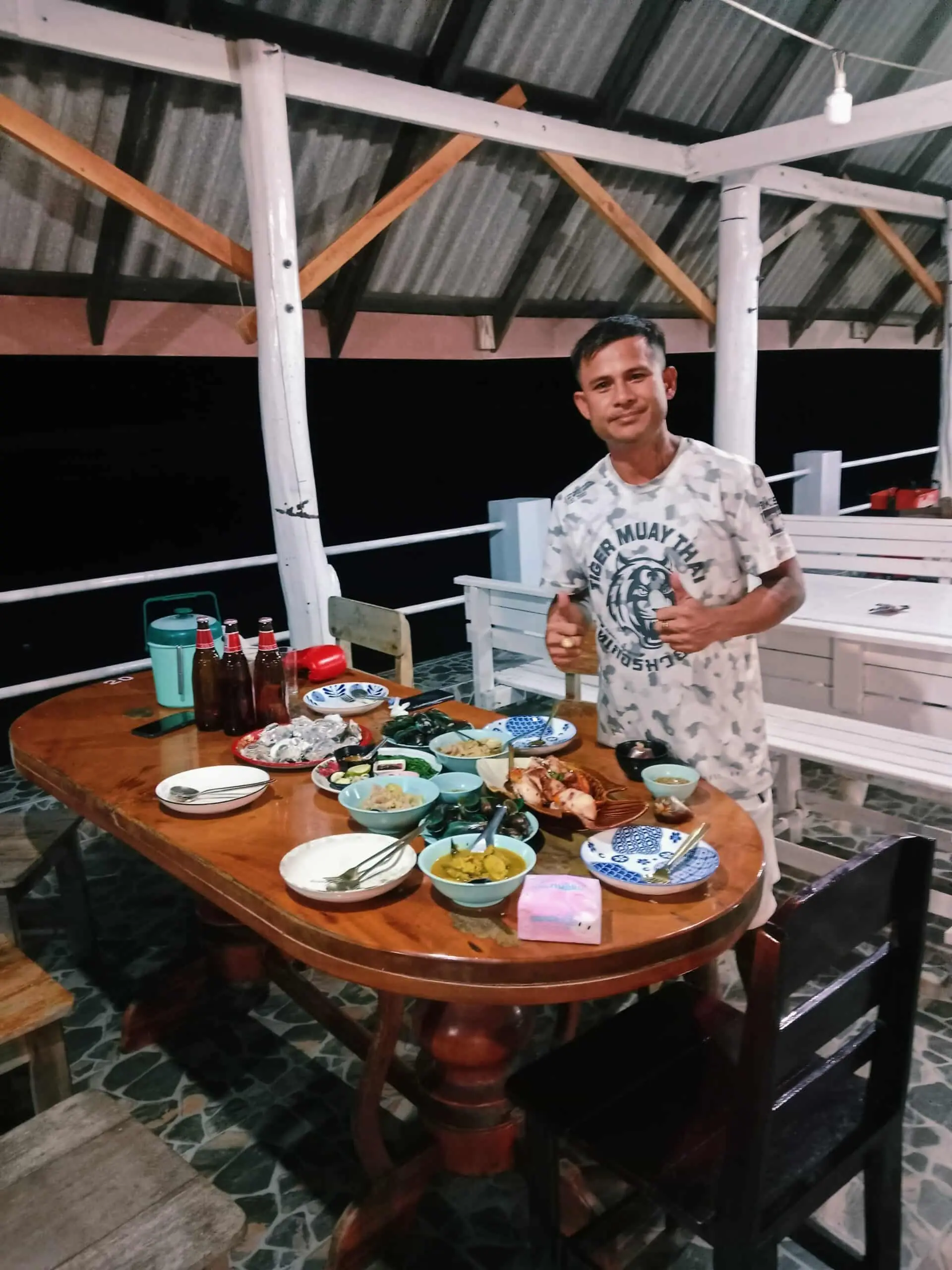 Our friend Bank smiling in front of a table laden with Southern Thai seafood dishes.