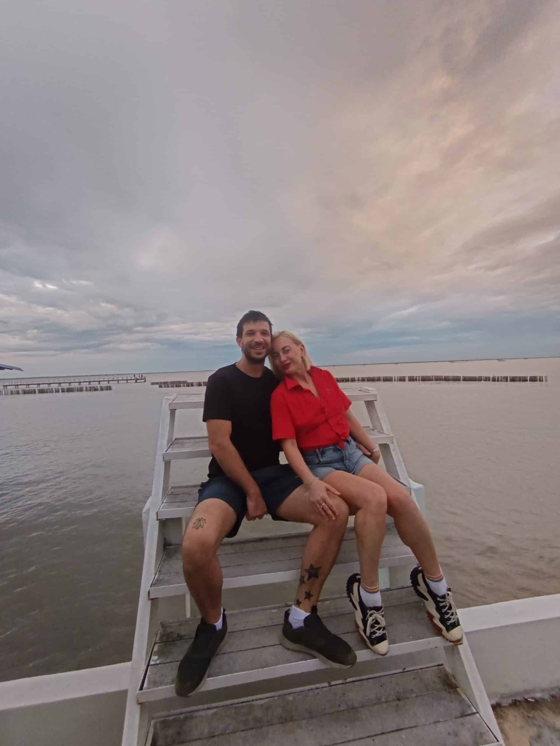 A romantic photo of Oliver and Natalia with the sea behind them at Bank's family restaurant.
