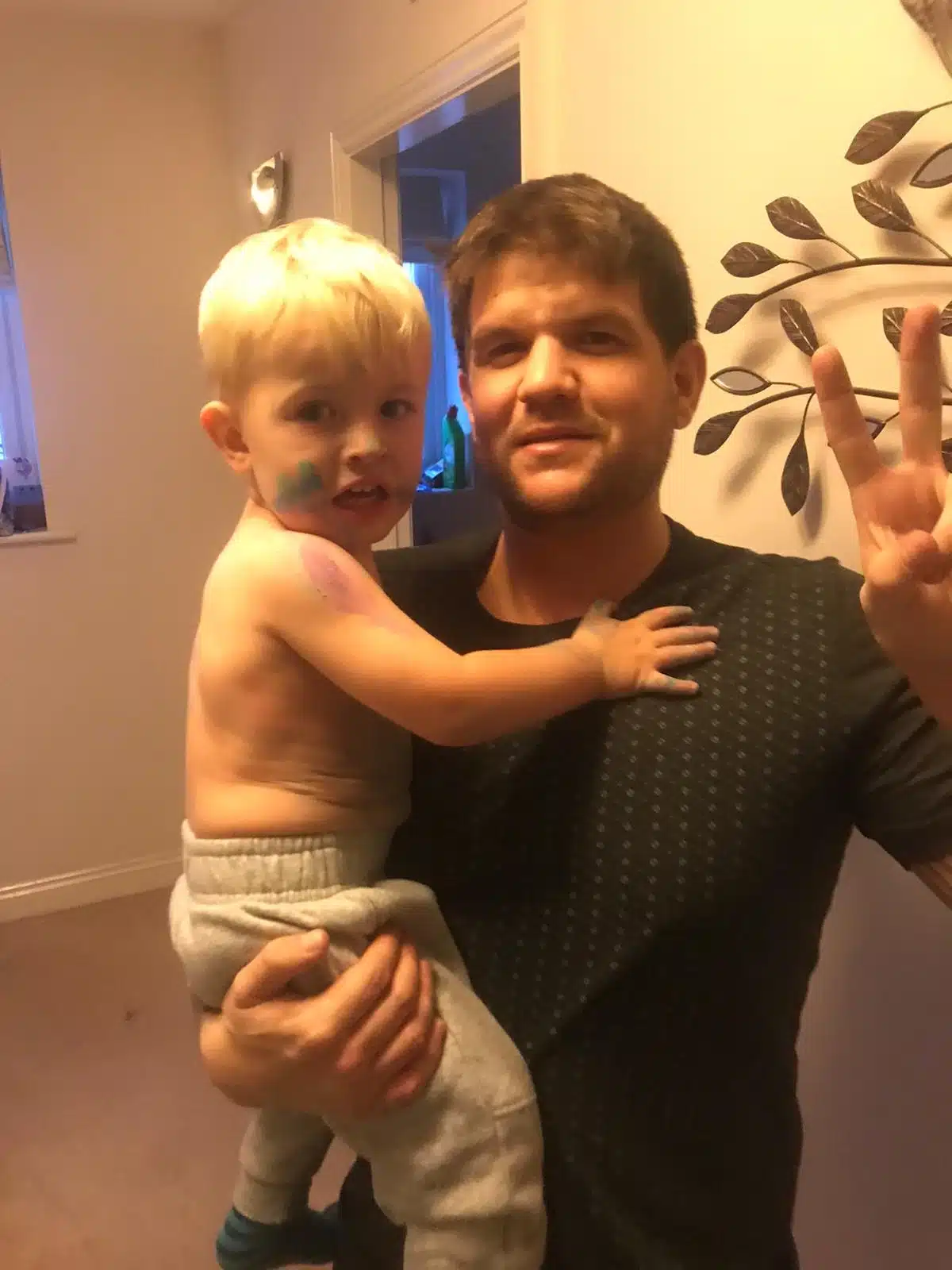 Daniel Mayerhoffer holding baby Victor making a peace sign