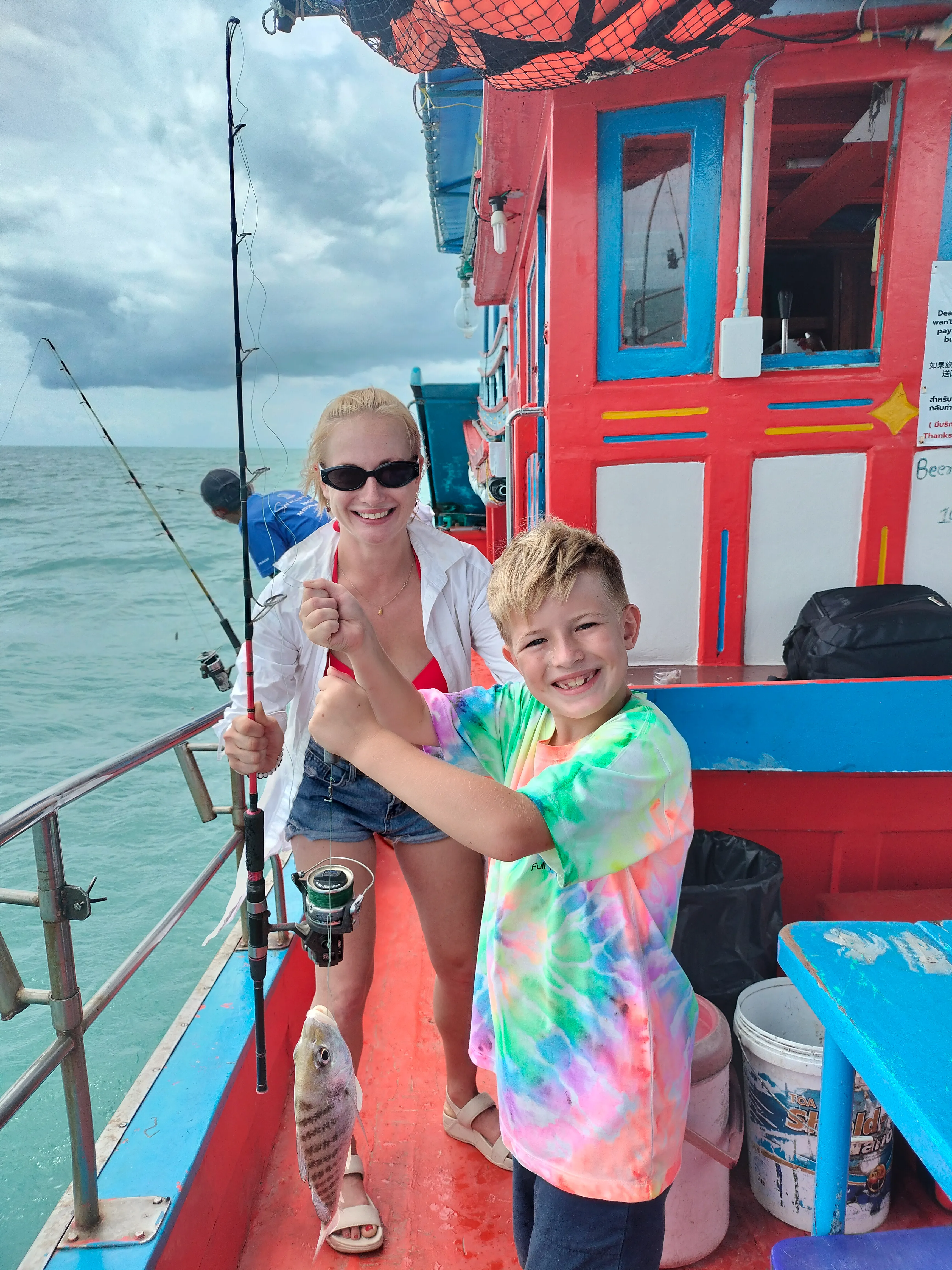 Victor and natalia on the fishing trip, victor just caught a fish and he is showing oliver who is behind the camera off the coast of koh samui