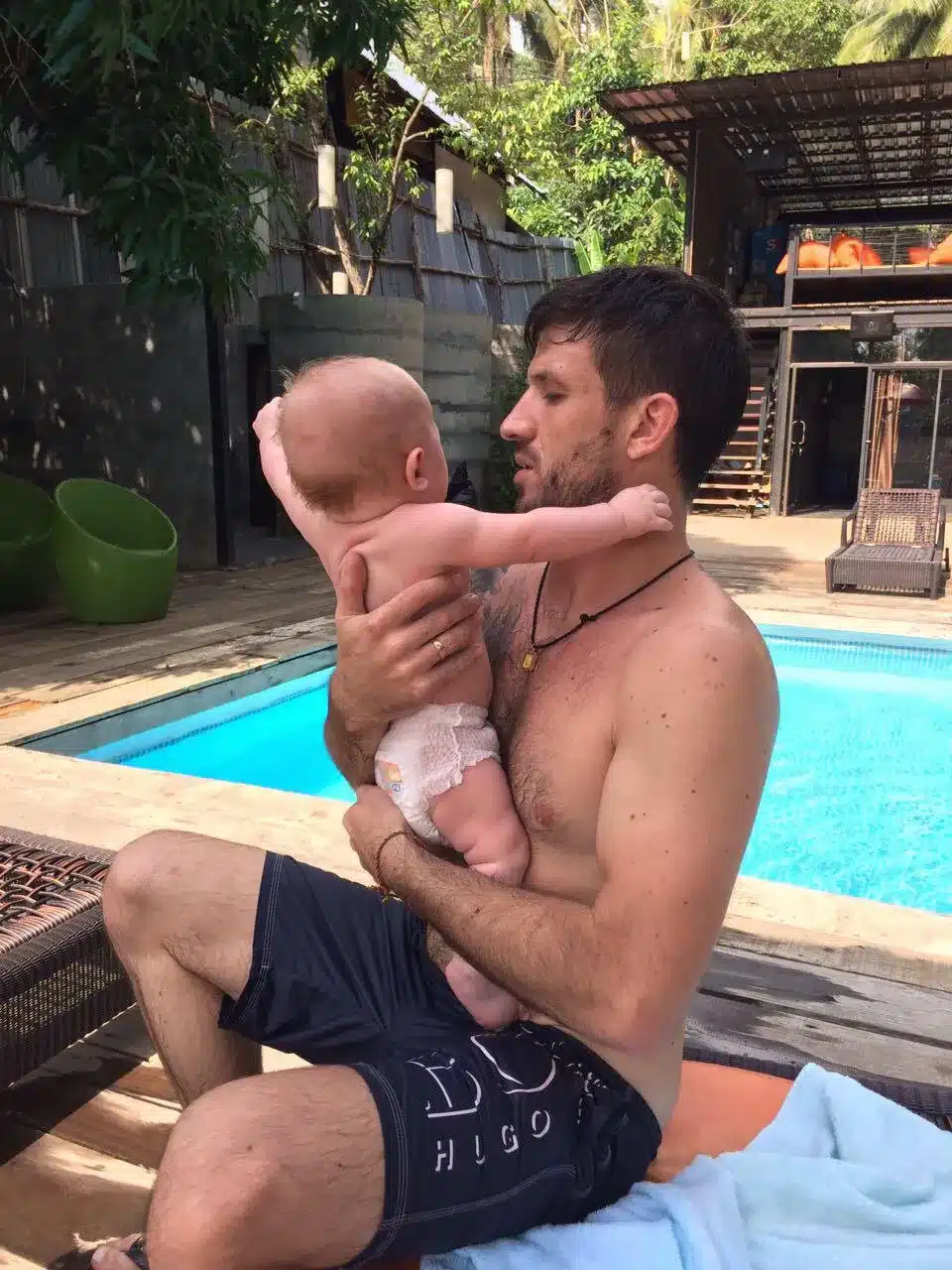Oliver holding infant son Victor (less than 1 year old) on Lonely Beach, Koh Chang—family travel moment