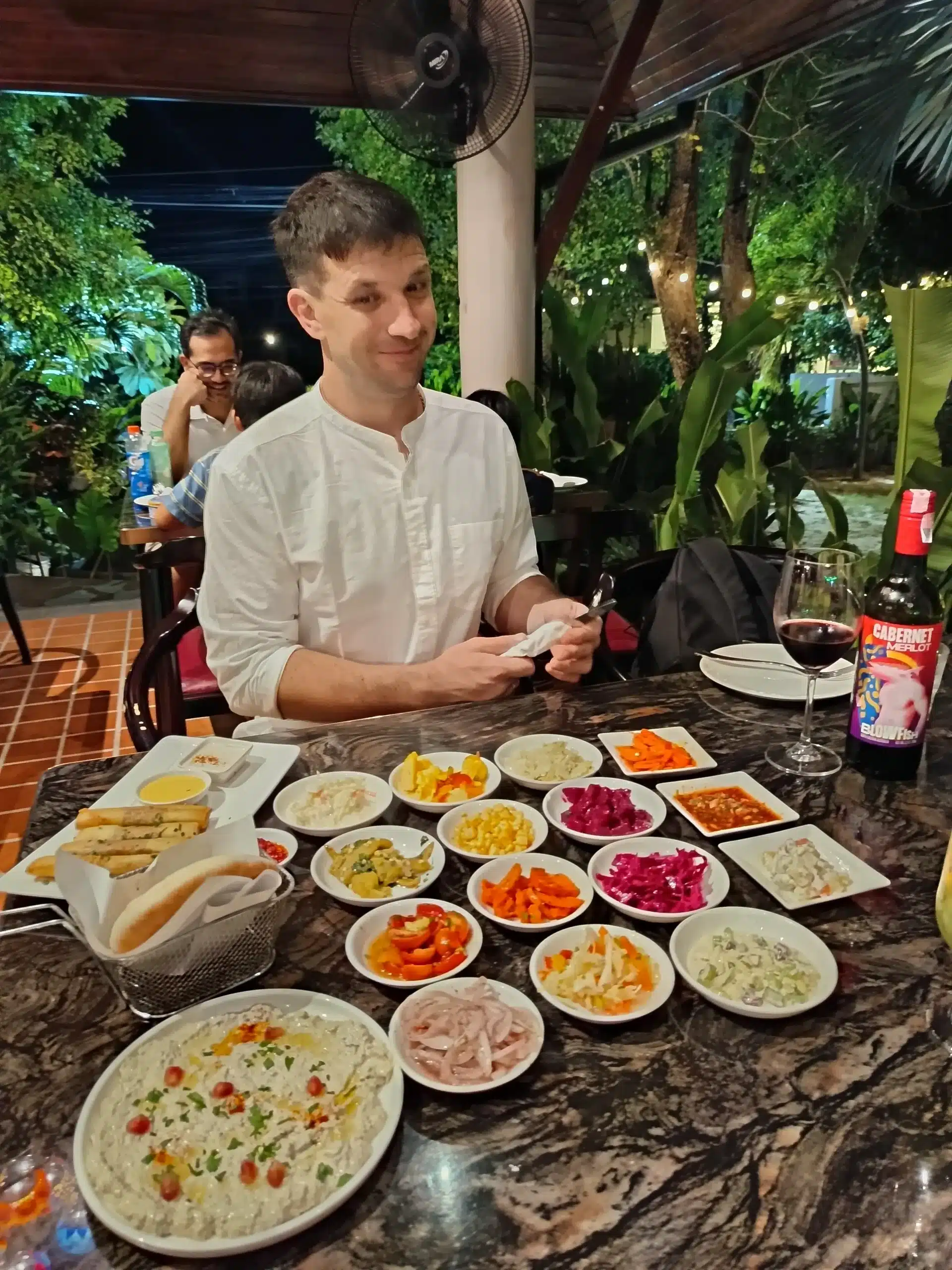 Oliver Mayerhoffer smiling at Ogen Hua Hin with hummus, bread, antipasti and shared dishes ready on the table
