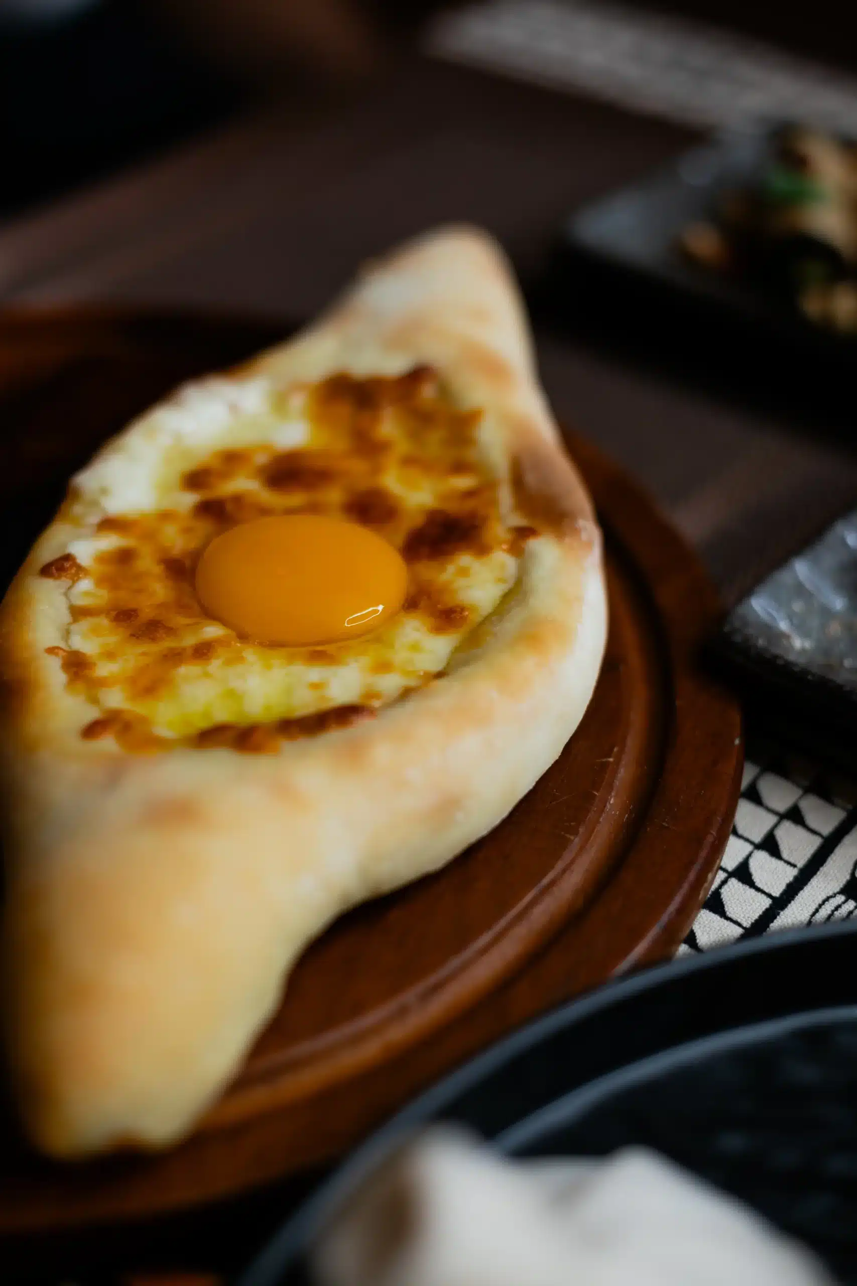 A close up shot of Adjarian Khachapuri at Hinkali House Hua Hin showing the melted cheese and egg, verified for the Victor-Tested standard of Mangoes and Palm Trees.