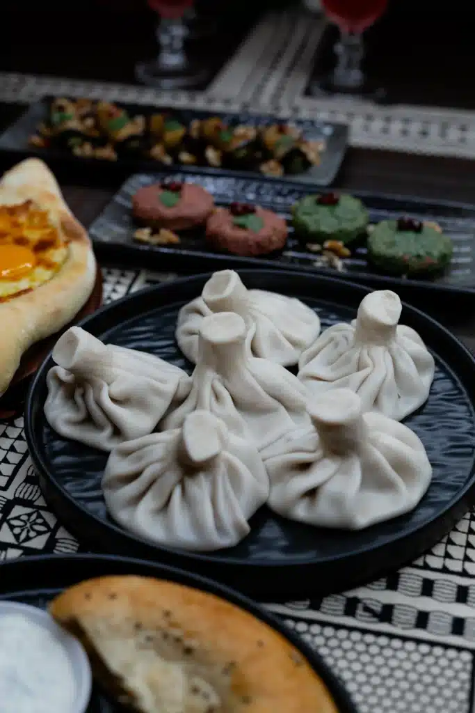A plate of authentic Georgian Khinkali soup dumplings resting on a table, demonstrating traditional Georgian dumpling etiquette during a family meal by Mangoes and Palm Trees.