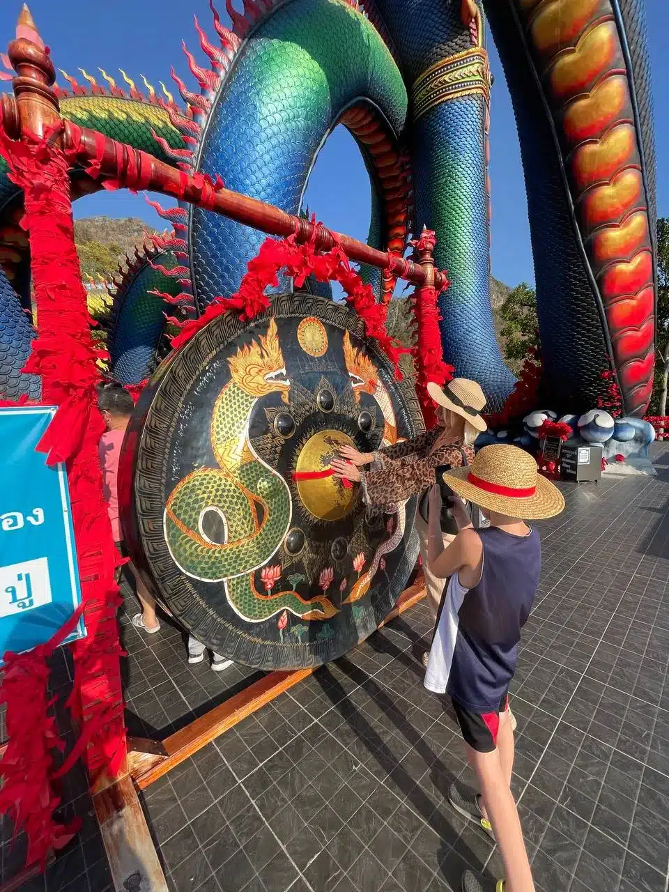 Victor Mayerhoffer striking the dragon-adorned gong at Wat Tham Chaeng