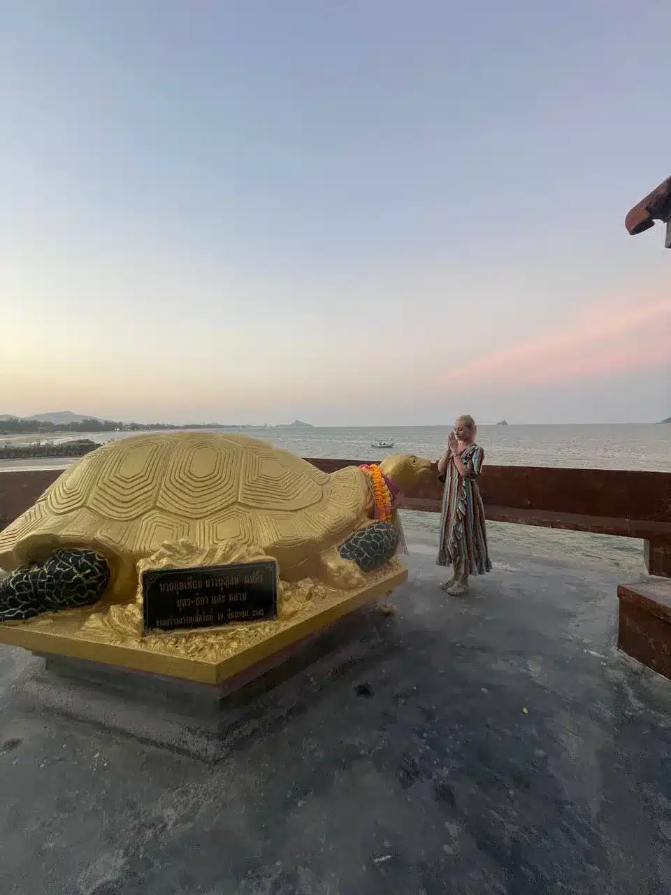 Natalia Mayerhoffer standing in front of the big gold turtle statue at Wat Tham Khao Tao Hua Hin