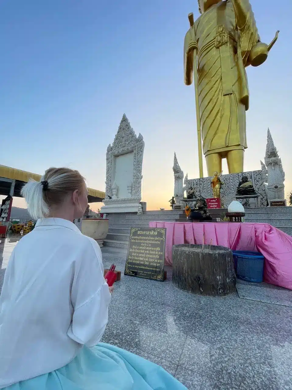 Natalia Mayerhoffer kneeling view from behind in front of big standing Buddha during Hua Hin fieldwork