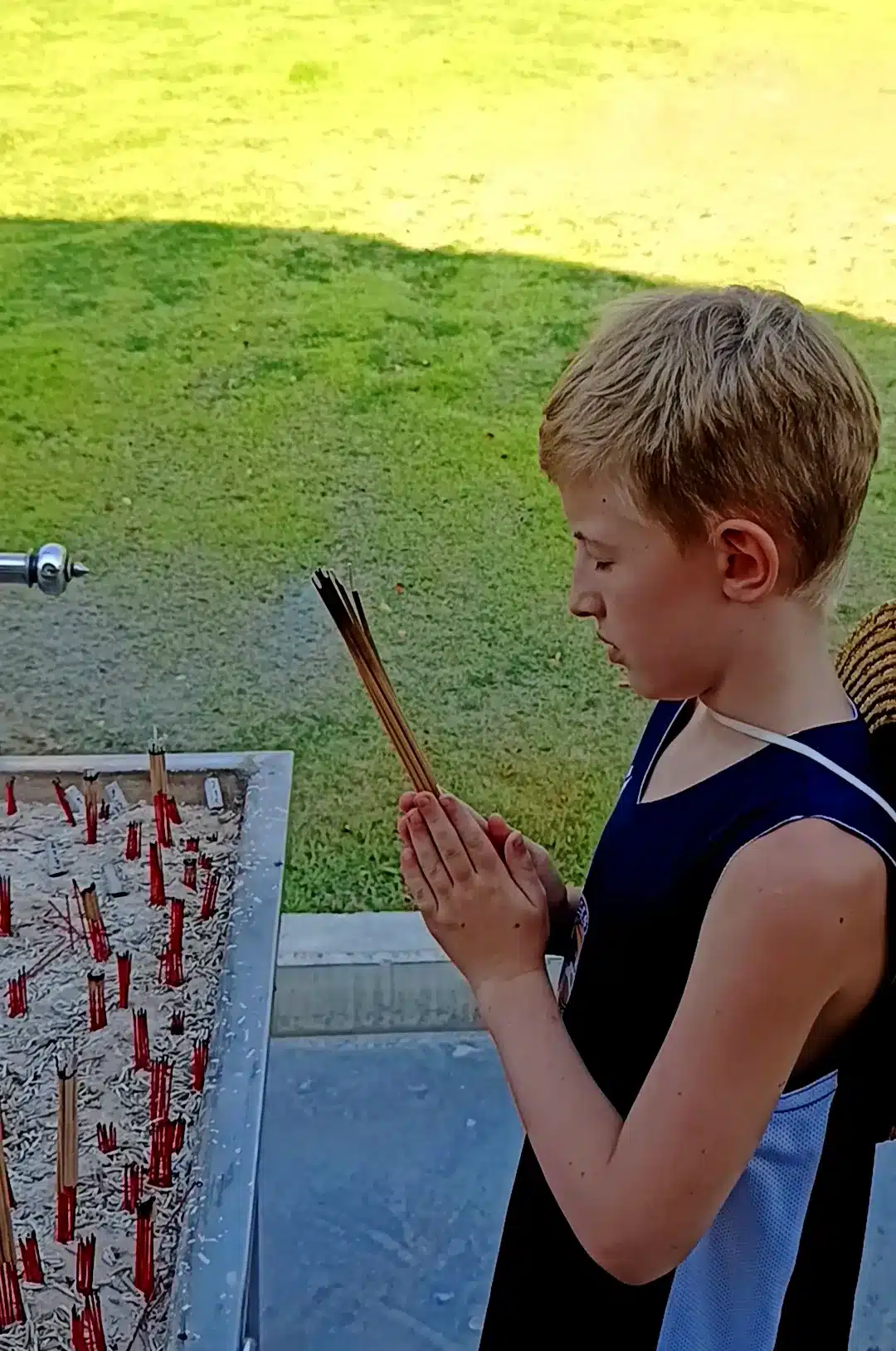 Victor praying with incense in his palms eyes closed spiritual moment showing his maturity and respect of cultures for such a young age