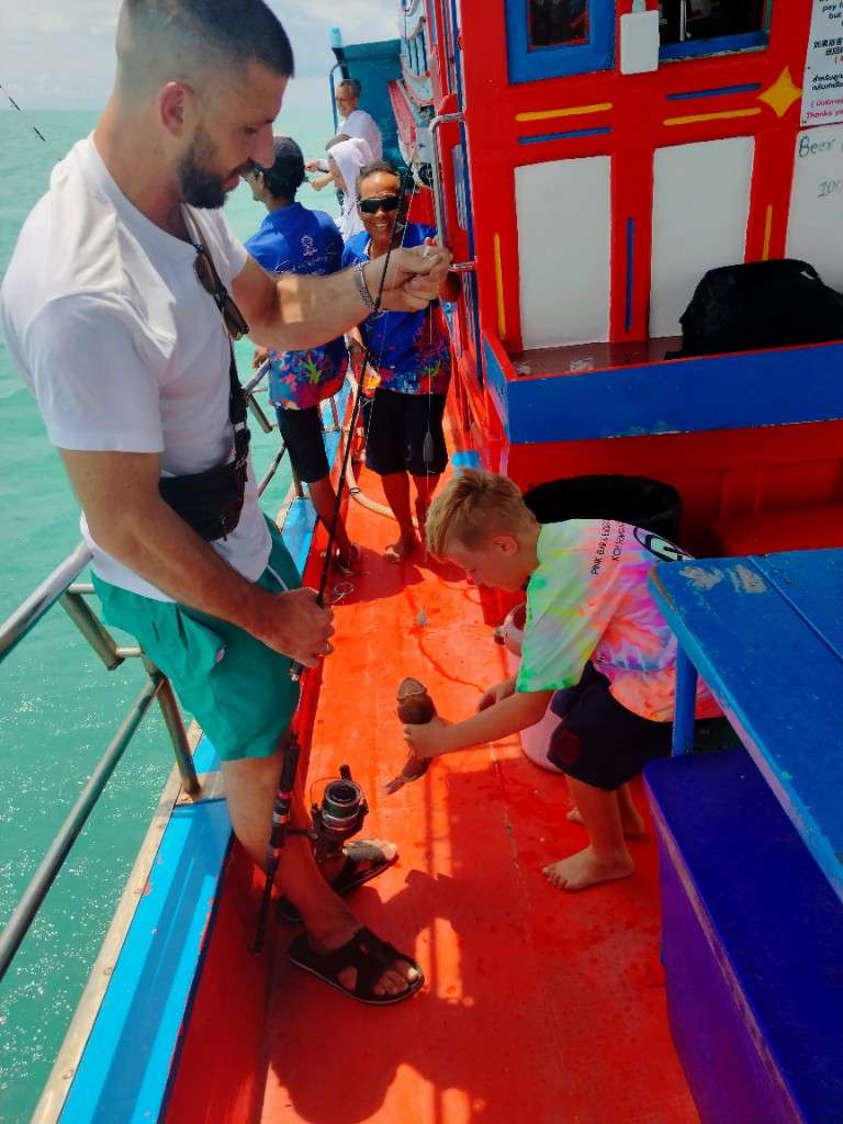 Victor unhooks a grouper on the Mr. Tu fishing boat deck with crew nearby, Koh Samui